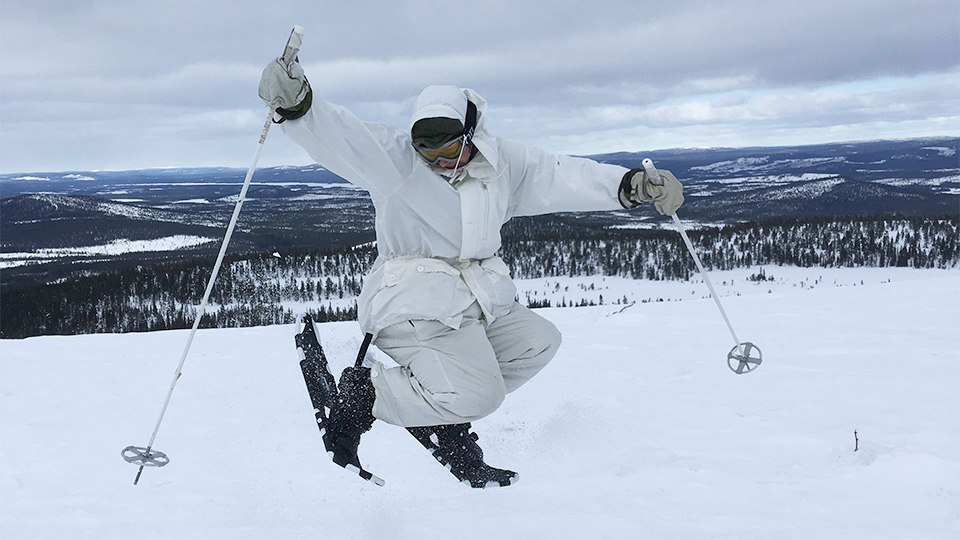 En elev i vinterlandskap gör ett högt skutt stående på skidor.