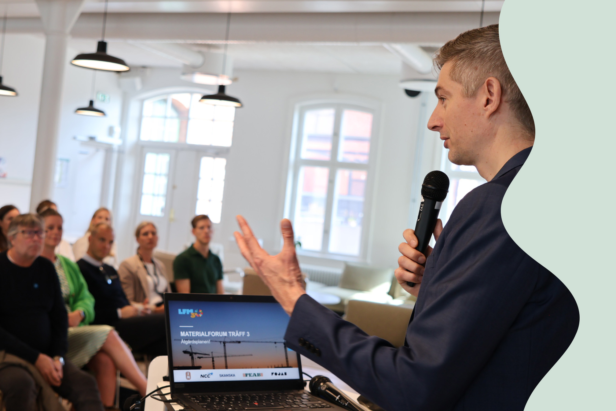 En man i kavaj från LFM30 står och pratar framför en publik.
