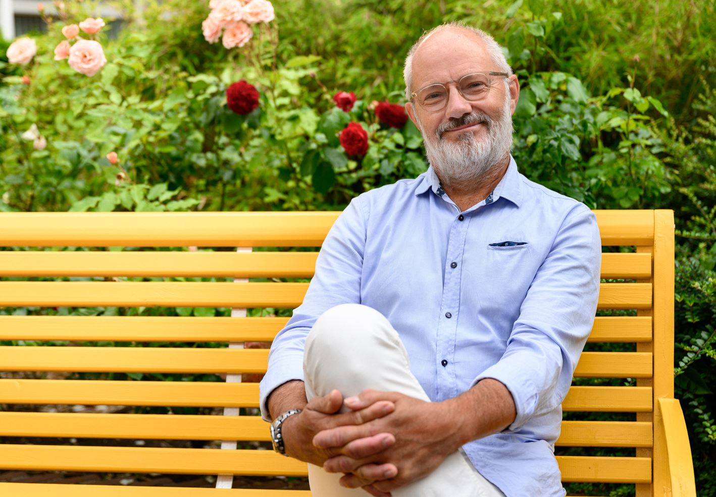 Fredrik har blå skjorta, grått hår och skägg och glasögon.