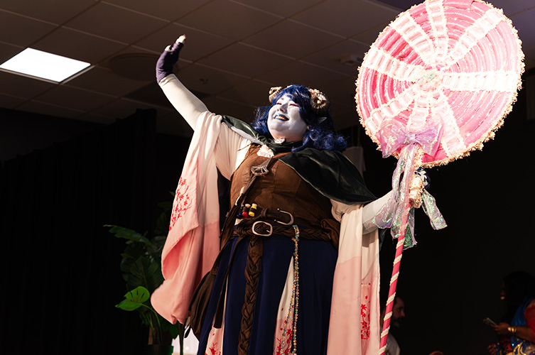 En person utklädd i cosplay ler och vinkar.