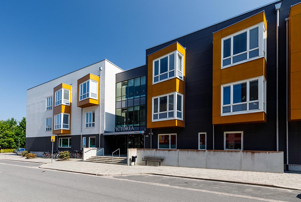 Boendets fasad är stilren och modern i gult, svart och vitt.