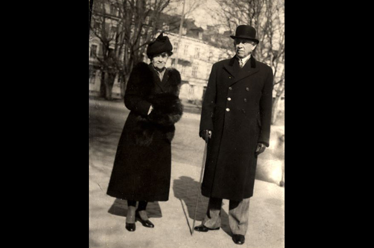 Axel och Gretha Cronquist står vid en gata med träd i bakgrunden i Malmö ca 1945. Fotograf okänd/Malmö Museer.