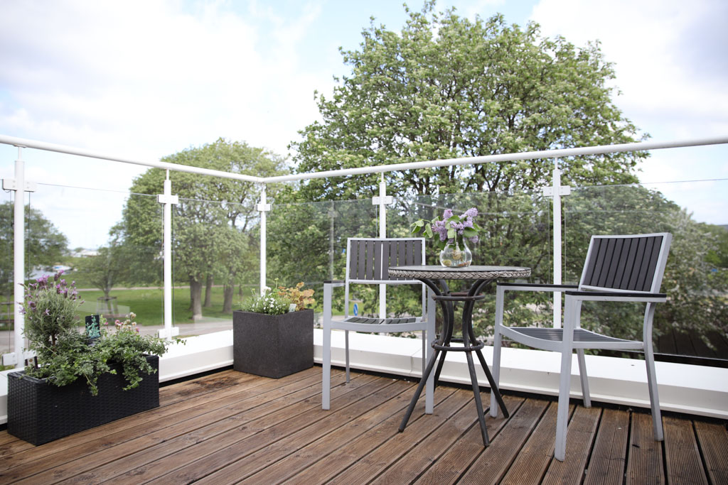 På den stora och luftiga balkongen har man utsikt över grönområdet.