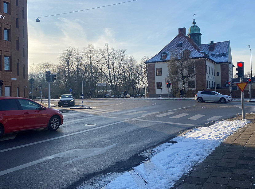 Lilla Nygatan i framtiden, där Raoul Wallenbergs park har blivit större och det finns mer plats för gående. En cyklist väntar vid överfarten, en grön MalmöExpressen-buss kör längs gatan. Illustration.