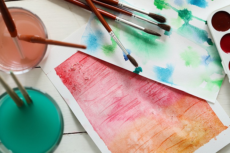 Färglada papper, vattenfärg och målarpenslar.