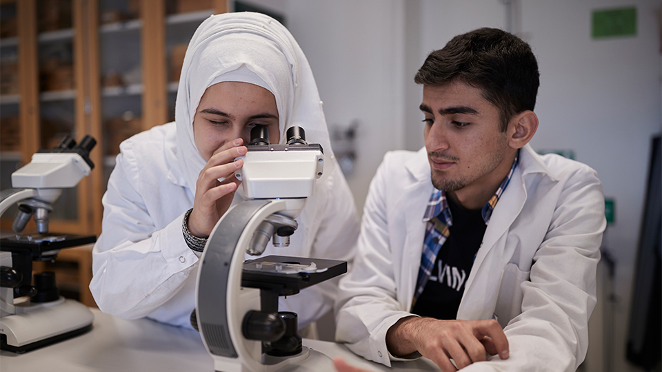 Två elever vid ett mikroskop