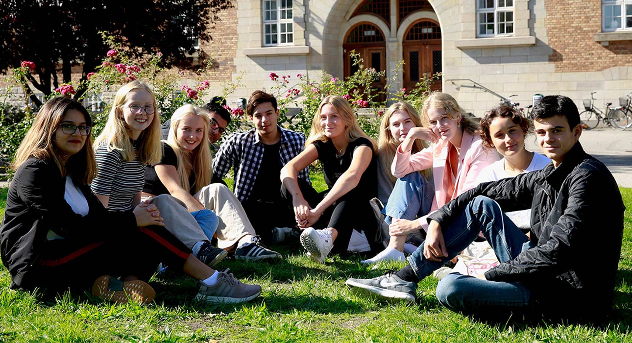 Elever sittande i gräset på skolgården