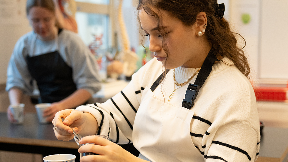 Elev som mäter upp något i en kopp i en laborationssal .