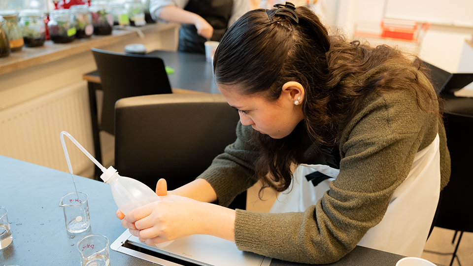 Elev som mäter upp vätska i ett kärl i en laborationssal.