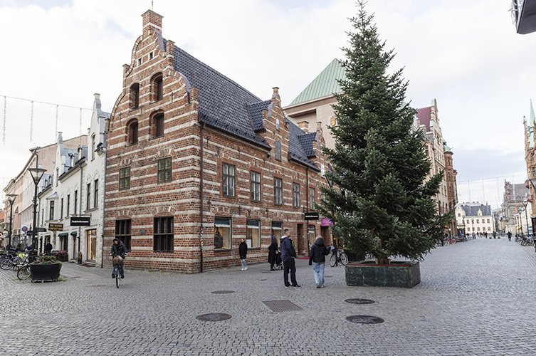 Ståtlig byggnad på hörn. En stor julgran står till höger.