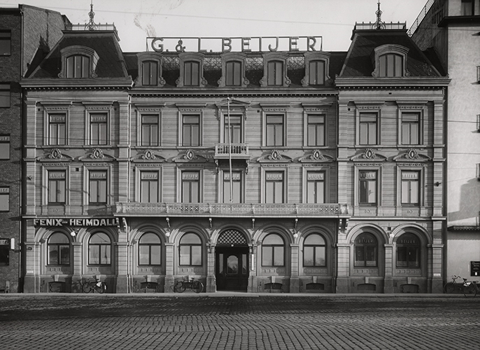 Äldre fotografi på Beijerska husets fasad, ett pampigt trevåningshus. På husets tak står en stor skylt med texten G. & L. Beijer