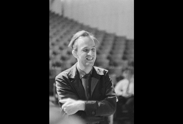 Äldre svartvitt foto på Ingmar Bergman, i bakgrunden en teatergradäng.