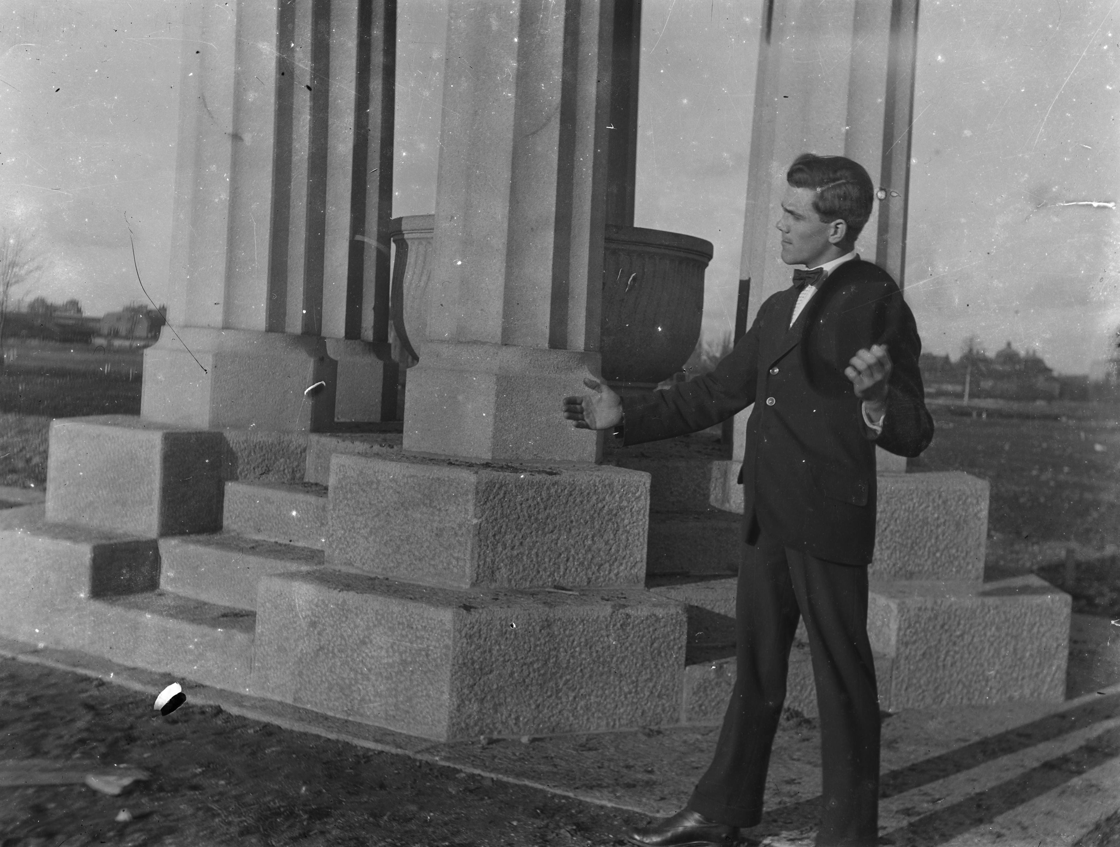 En ung man står vid fontän med pelare.