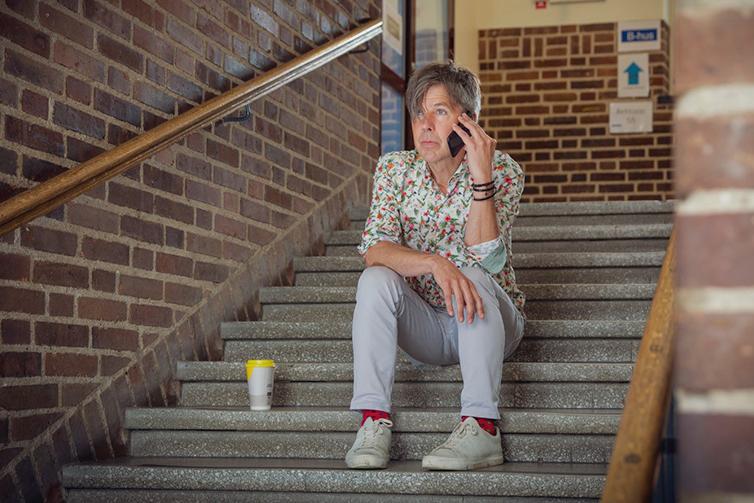 Yerk sitter i trappan med kaffekopp och pratar i telefon.