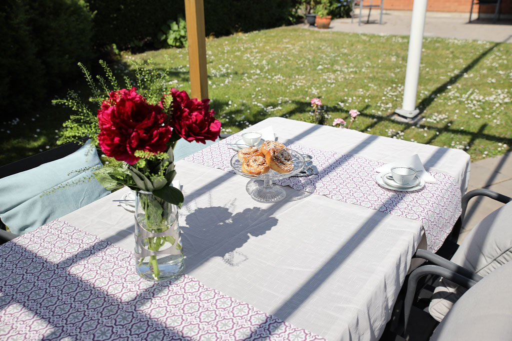När det vankas fika utomhus i den lugna trädgården dukas det gärna upp med fin duk, kaffekoppar och blommor.