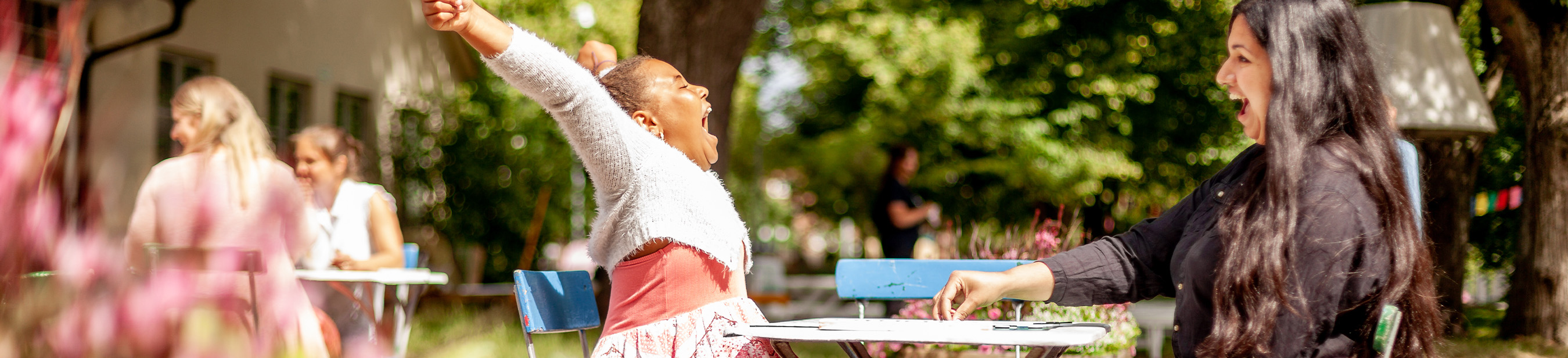 Ett barn och en vuxen som sitter vid ett bord och spelar spel. Barnet sträcker armarna upp i luften och ser glad ut.