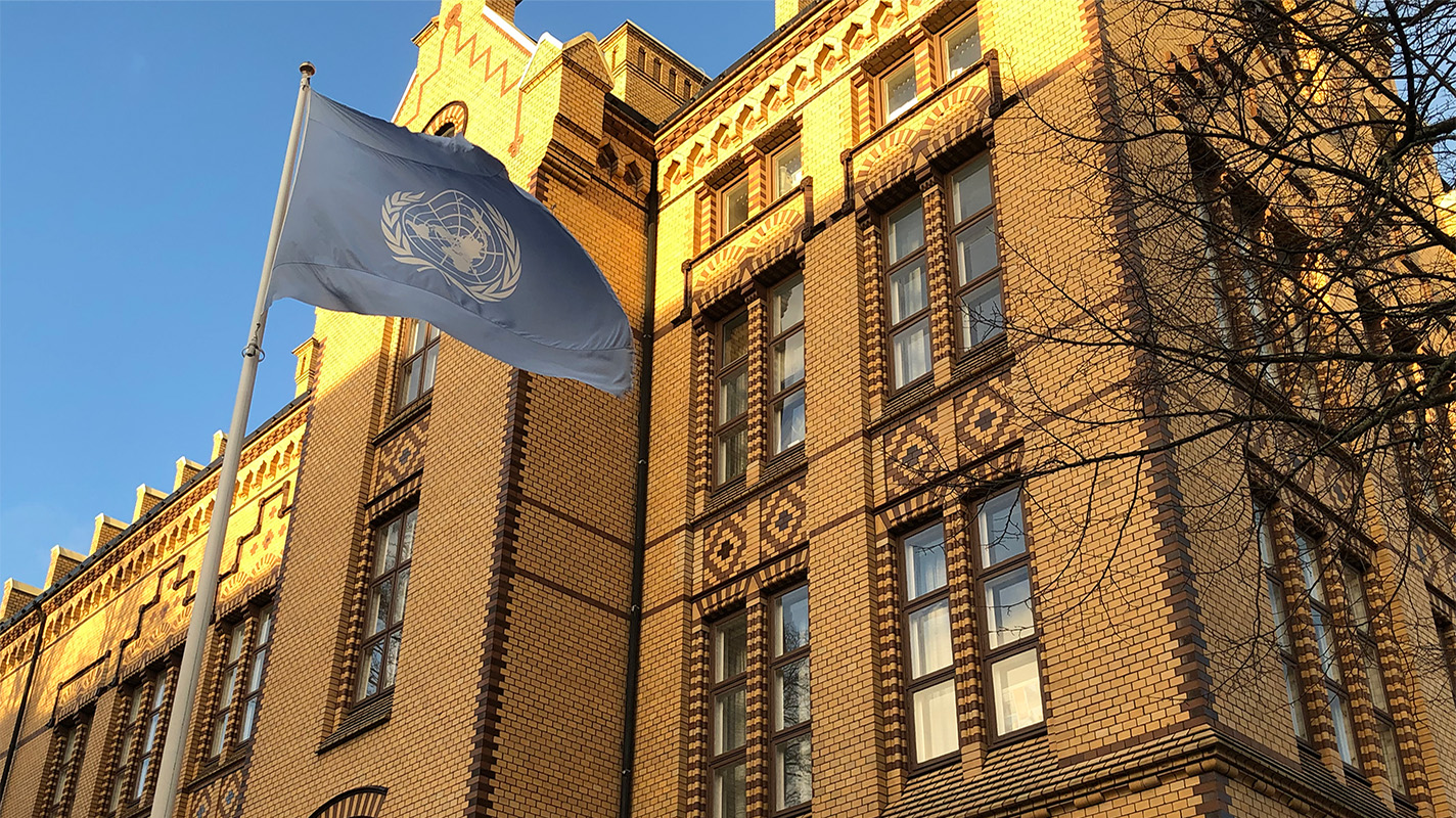 Exteriör bild på skolbyggnad med FN-flagga framför.