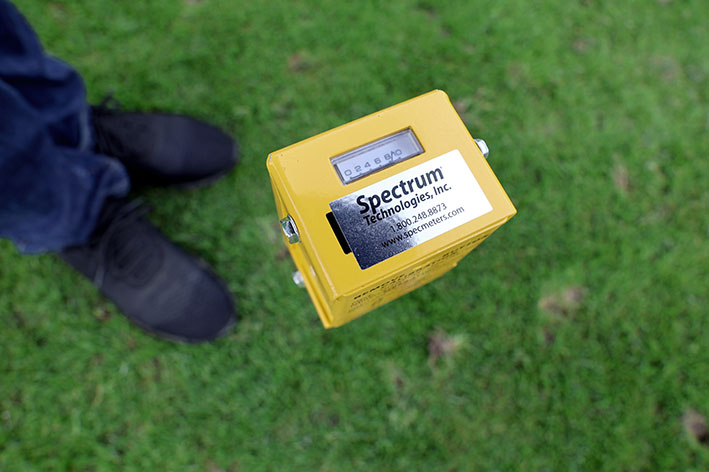 Bild på en gul fuktmätare som står nedstucken i gräset.