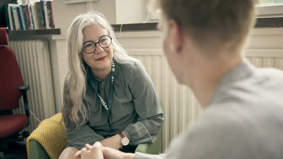 En elev sitter och samtalar med en kurator i informell miljö.