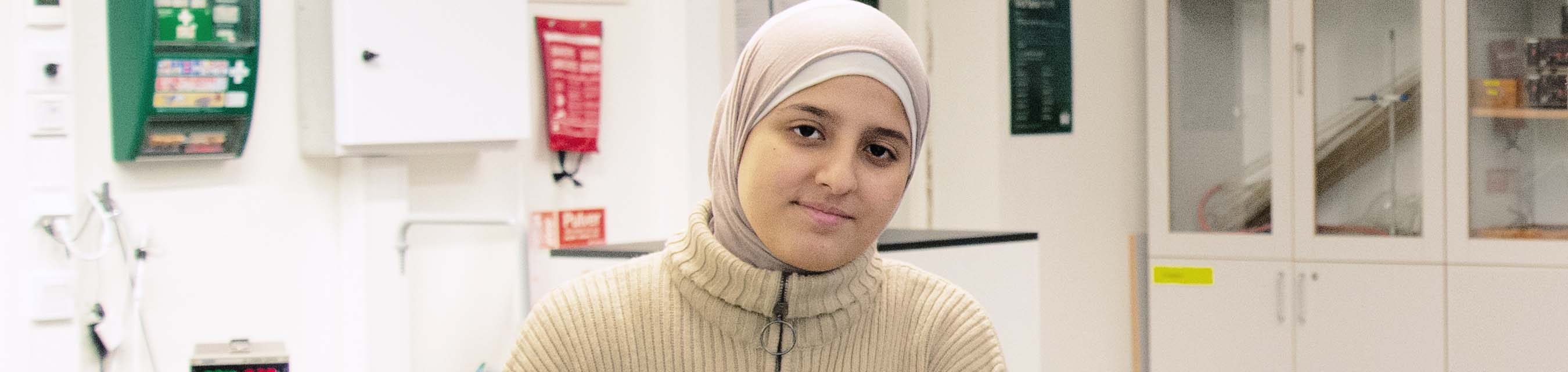 En elev iklädd hijab sitter i labbsalsmiljö