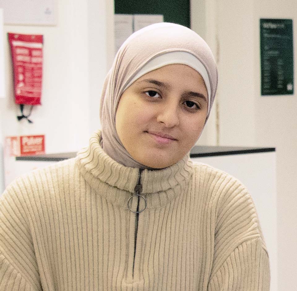 En elev iklädd hijab sitter i labbsalsmiljö.