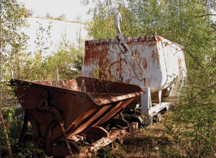 En gammal rostig metallkärra och container som står kvar i Limhamns kalkbrott.