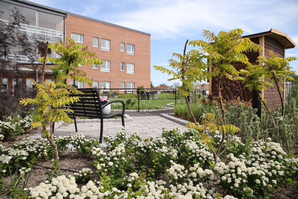 Framför den bruna tegelfasaden finns en lummig
trädgård där man kan sitta och njuta av alla blomsterarrangemang i rabatterna. 