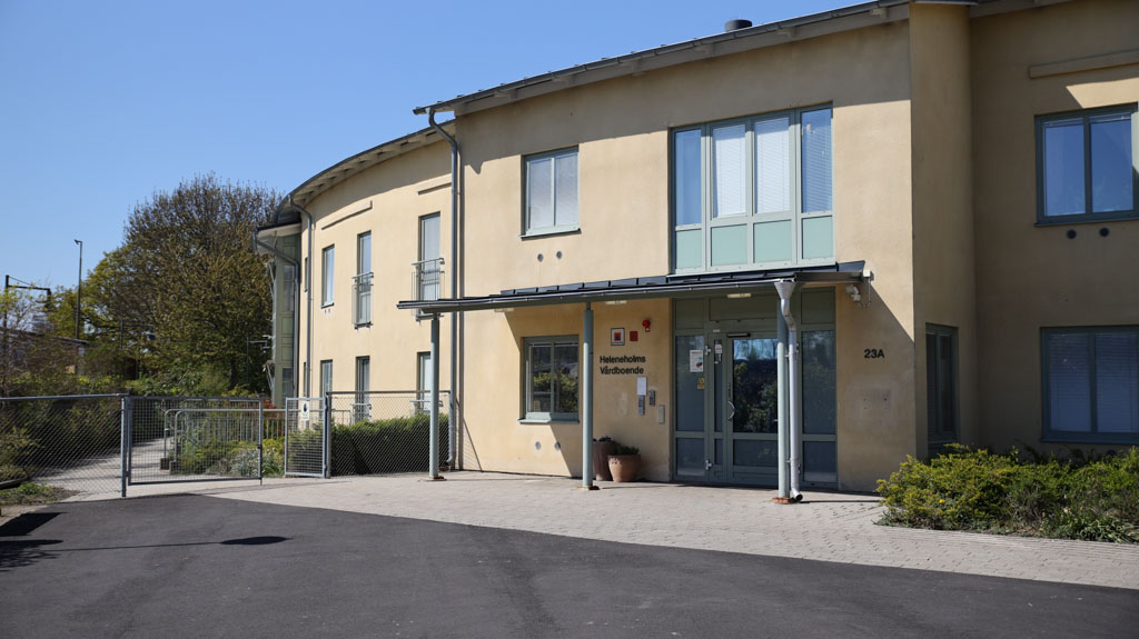 Tvåvåningshus i ljusgul fasad med gråa detaljer.