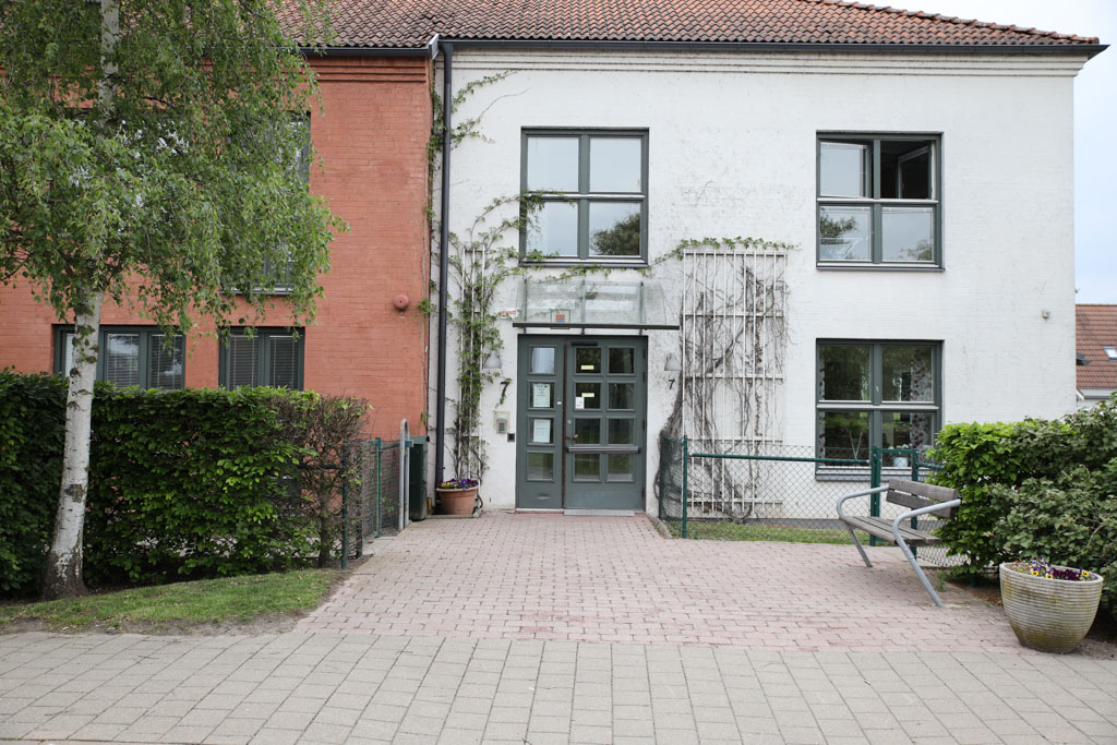 Växter slingrar sig längs husets vita fasad med grågröna detaljer på
dörr och fönster.