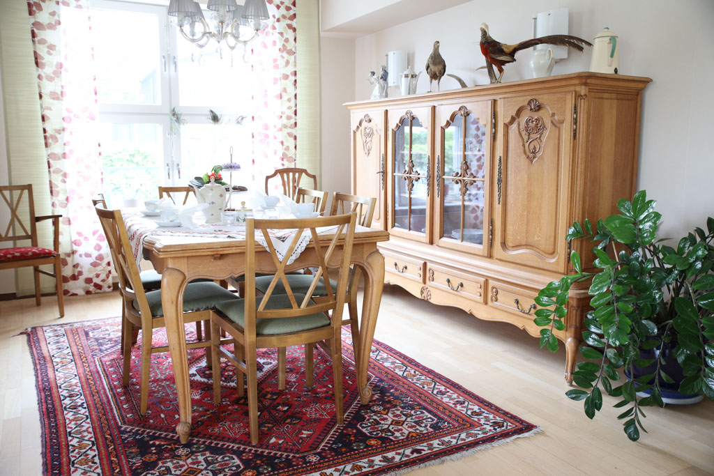 Matgrupp och stort skåp i trä ramar in den gemensamma matsalen.