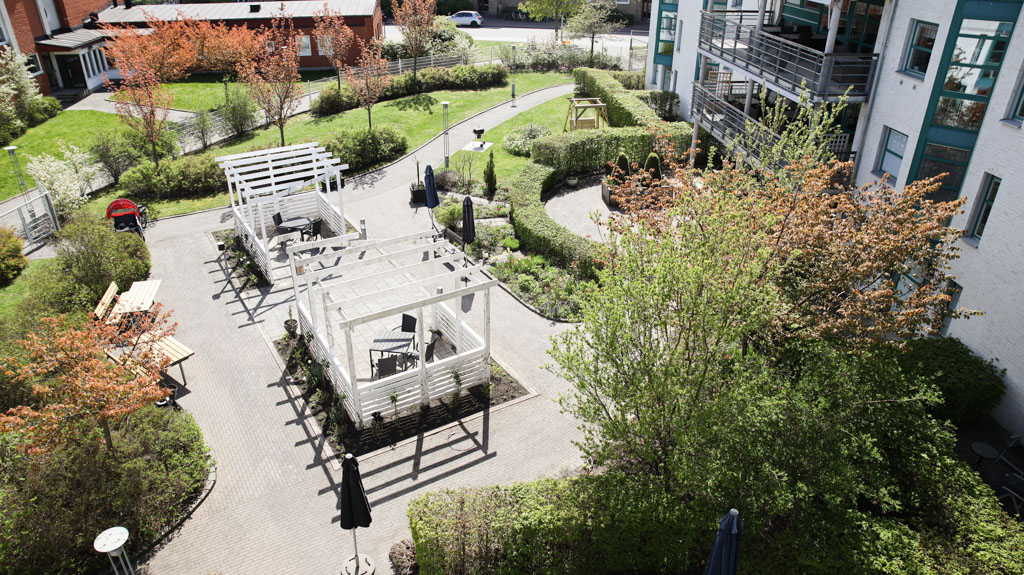 Öppna stora ytor med mycket grönska och olika sittpartier
ser vi ovanifrån boendets uteplats.