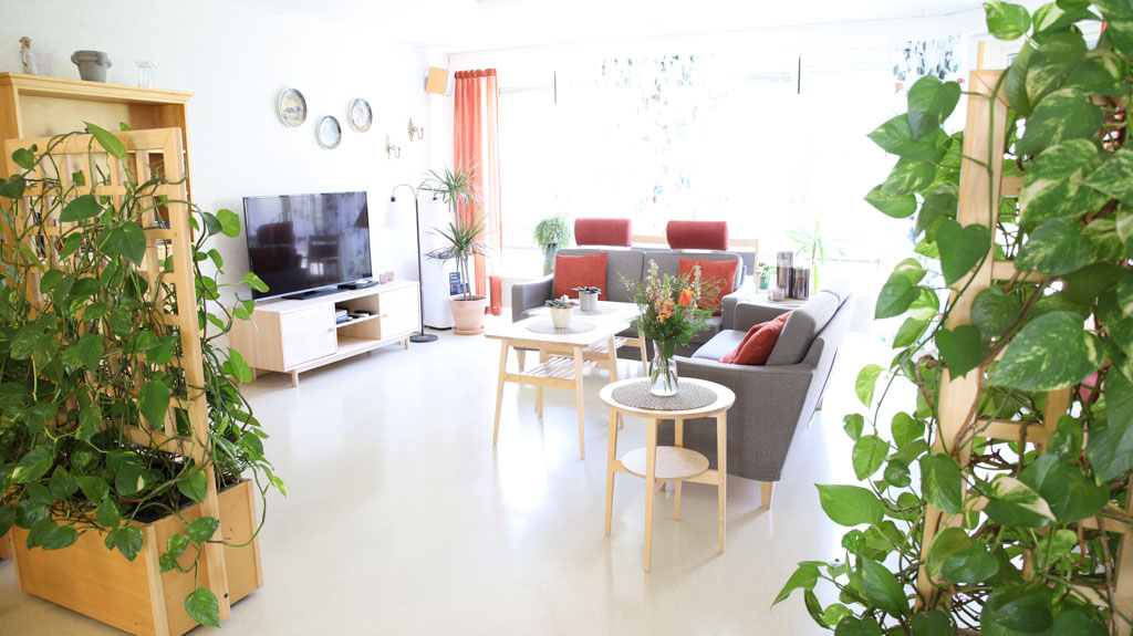 Mycket blommor och grönska får det att se hemtrevligt ut i detta
möblerade TV-rum.