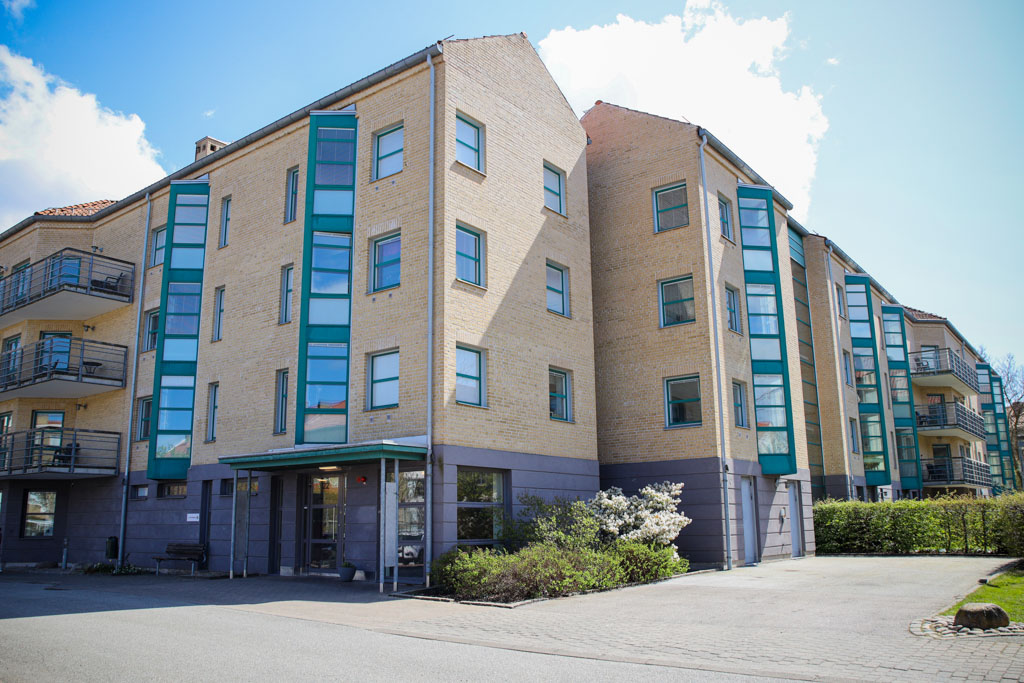 Ett ljusgult tegelhus med gröna detaljer i fyra plan.