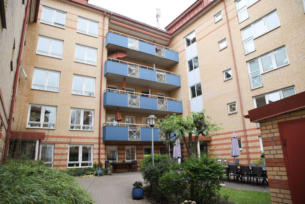 Högt tegelhus med blåa balkonger där man har överblick över innergården.