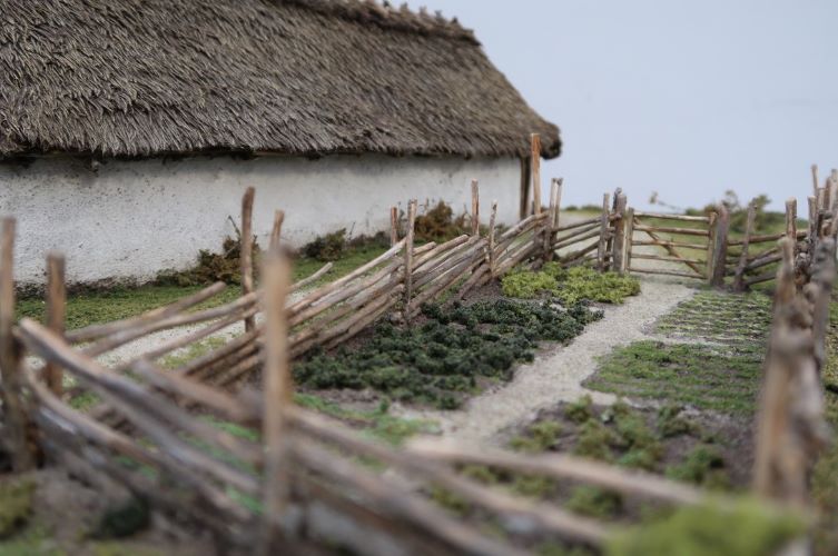 Miniatyrmodell av inhägnad trädgård i järnåldersmiljö.