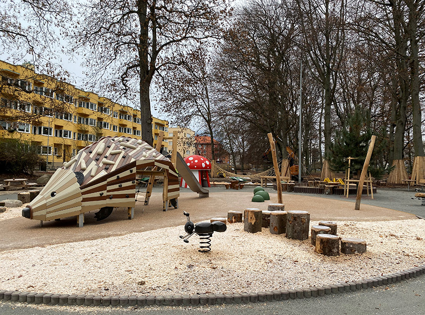 Flera olika lekkonstruktioner på lekplatsen. Den som tar mest plats är en stor igelkott som barn kan springa in och leka i. 