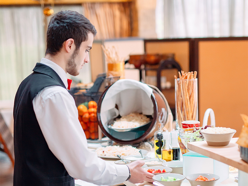 Frukostvärd på hotell dukar fram kontinental
frukostbuffé.