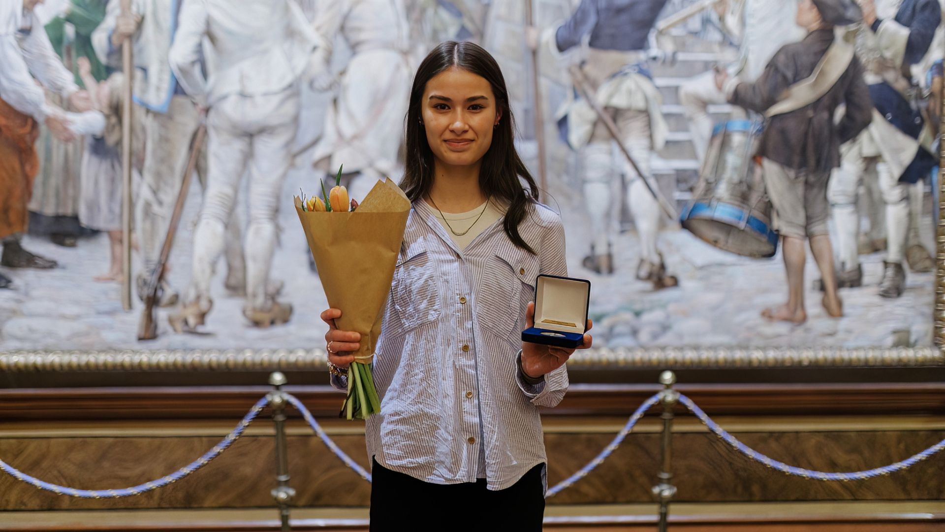 Indra Bodén i ljus skjorta håller upp sin medalj och blommor.