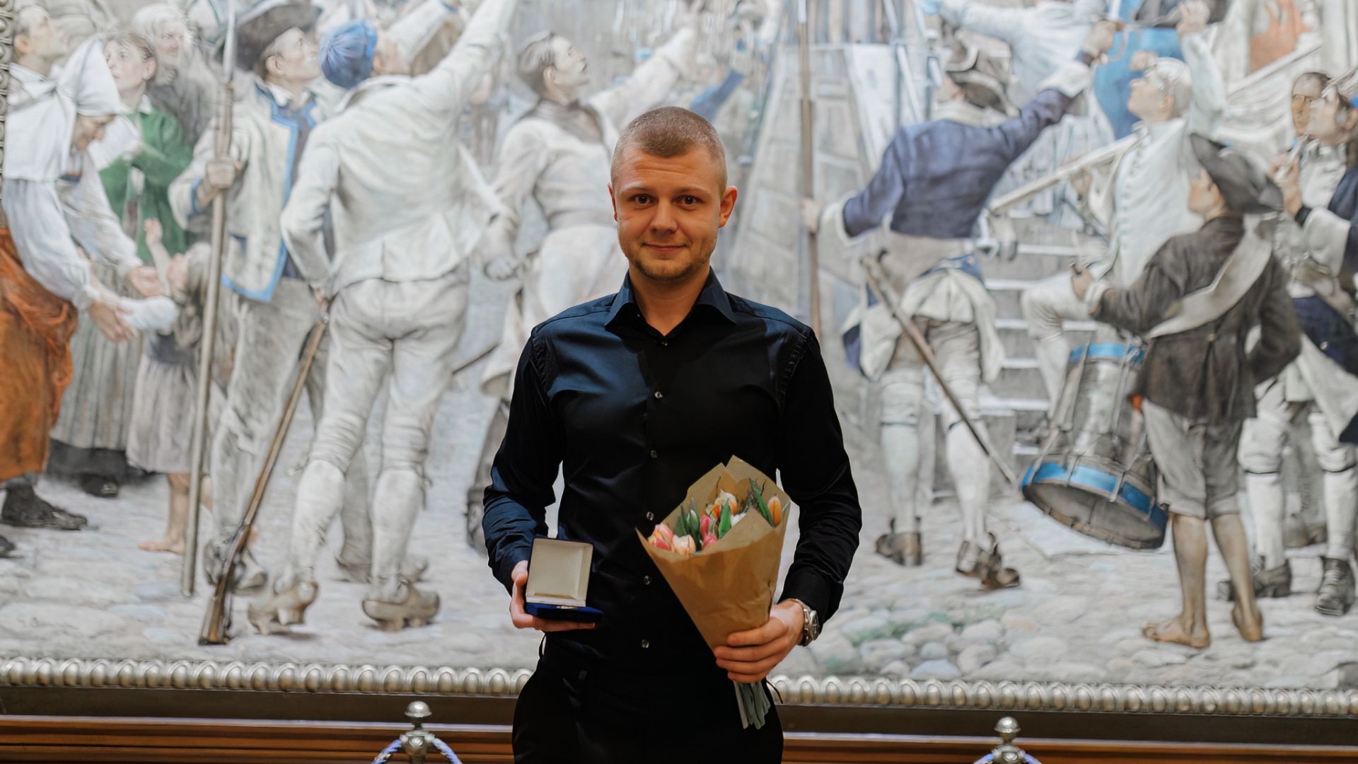 Viggo Öhrneman i mörk skjorta visar upp sin medalj som han mottagit.