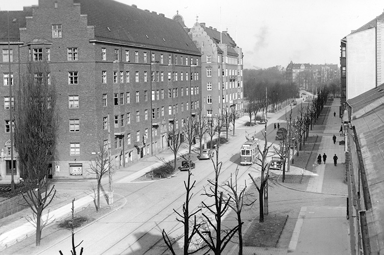Väg kantad av höga byggnader. Svartvitt foto.