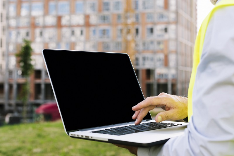 En person sitter utomhus med en laptop i knät.