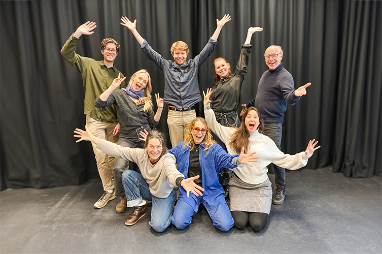 Ett tiotal vuxna poserar med glada miner och utsträckta händer. 