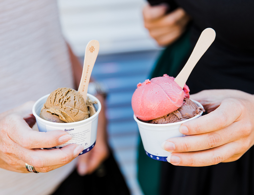 Två glassar i bägare som två hålls av två olika personer.