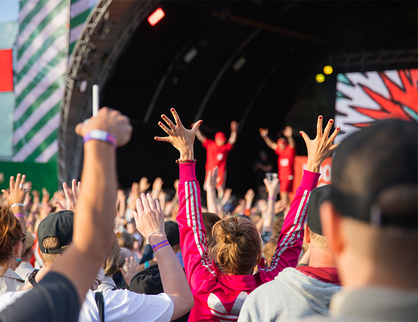 En pubilk framför en scen, många sträcker upp händerna