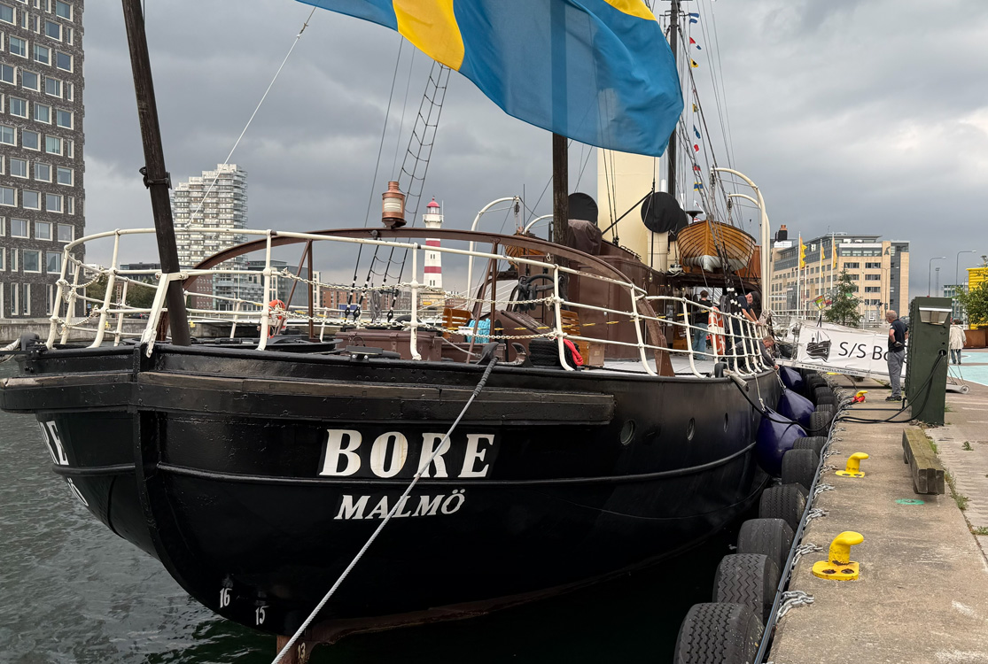 En svart båt av äldre modell, en så kallad ångisbrytare, med texten Bore i vitt ligger vid en kaj. En bit av svenska flaggan syns i överkant av bilden.