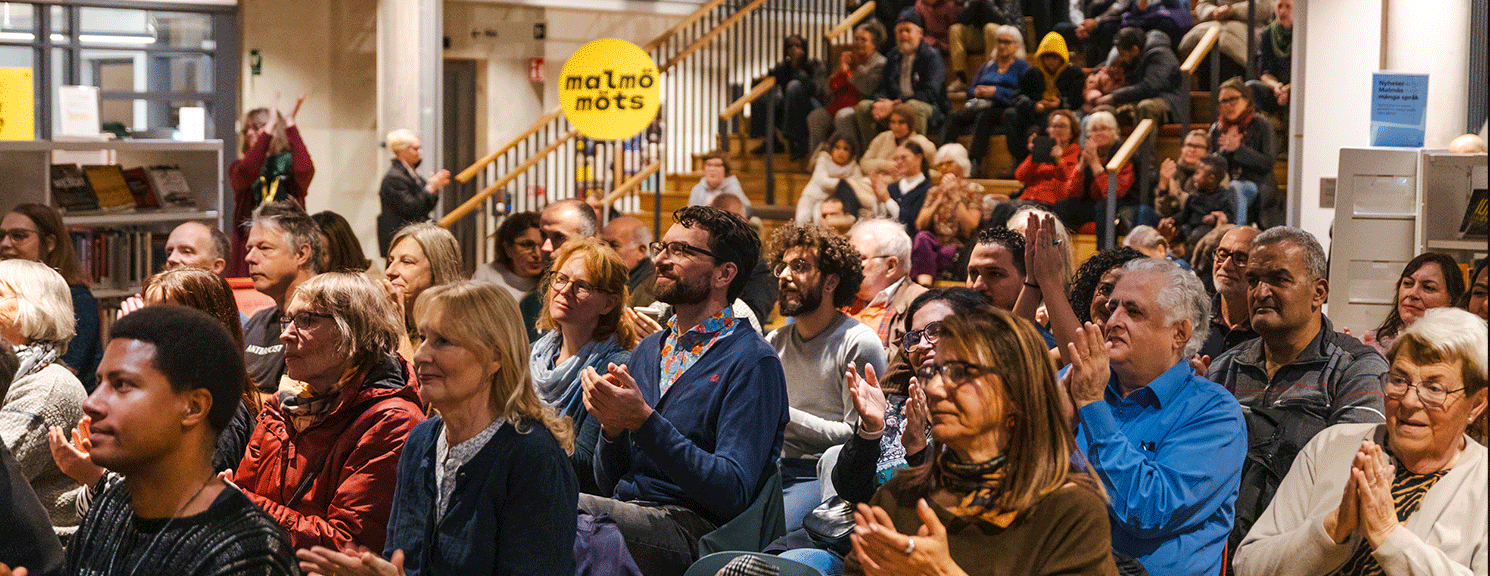 Många människor som sitter i en trappa inomhus.