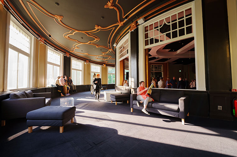 Olika grupper av personer sitter inne i en del av restaurangpaviljongen.