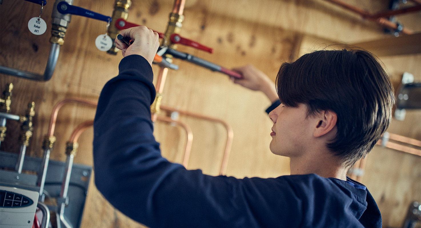 Elev skruvar åt ett rör.