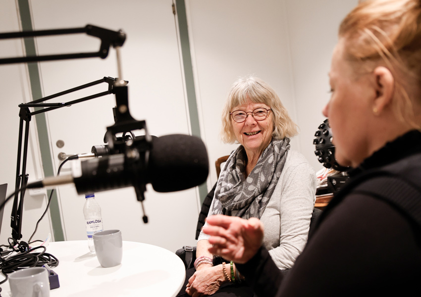 Monica och Annika sitter ner vid stora mikrofoner och samtalar.