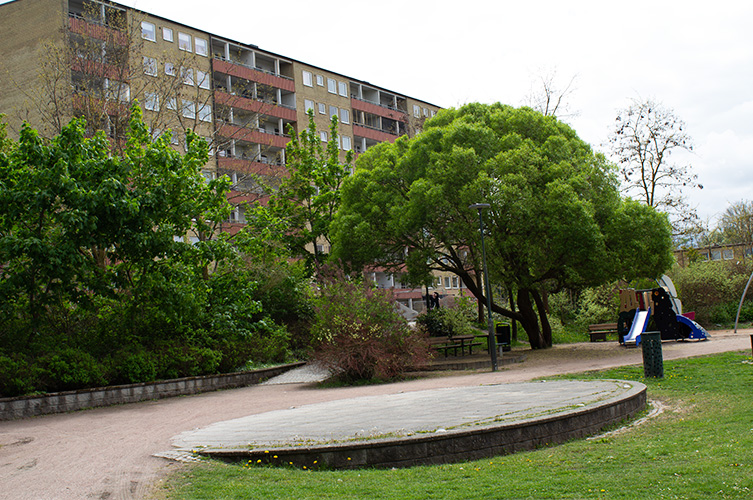 Mindre scenplatta i park med höghus i bakgrunden.